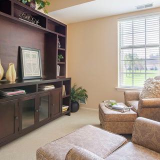 A cozy living room featuring an entertainment center with shelving, a large window allowing natural light, and comfortable seating.