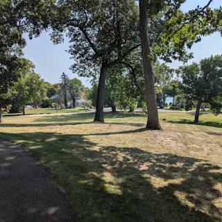 A serene view of a park with lush trees and open grassy areas.