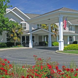 A residential building with a landscaped entrance and blooming flowers.