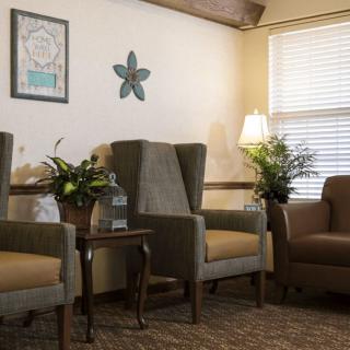 A cozy living room with comfortable chairs, plants, and warm lighting.