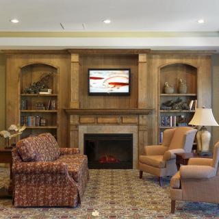A cozy living room with a fireplace, wooden bookshelves, and comfortable seating.