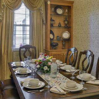 An elegant dining room with a beautifully set table and a china cabinet in the background.