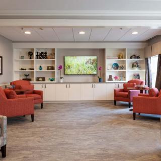 A cozy living room with orange armchairs and a television surrounded by shelves.