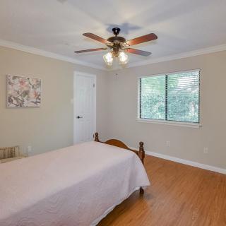 A cozy bedroom with a single bed, ceiling fan, and hardwood flooring.