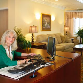A receptionist working at a modern office desk in a well-lit lobby.