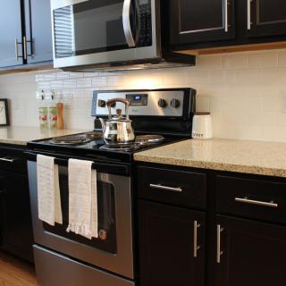 A modern kitchen with stainless steel appliances and dark cabinetry.