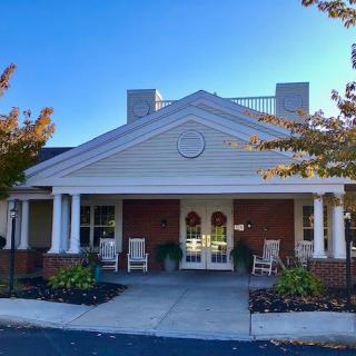A welcoming building entrance with columns and a porch, framed by landscaping.