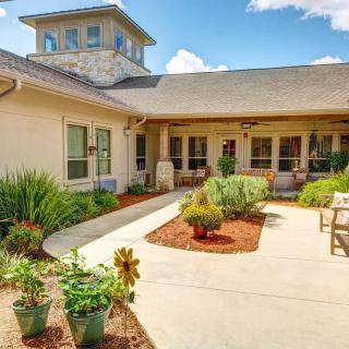 A peaceful courtyard garden with lush greenery and a seating area, adjacent to a building.