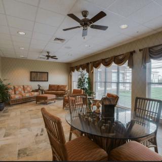 A spacious living room with comfortable seating, ceiling fans, and large windows.