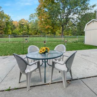 A tranquil backyard patio with a glass table and four chairs, perfect for outdoor relaxation.