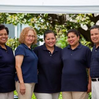 A team of five people wearing matching uniforms posing outside.