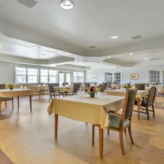 A spacious and well-lit dining room with neatly arranged tables and chairs.