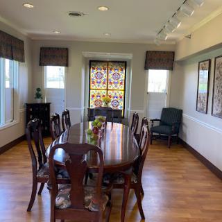 A cozy dining room featuring a wooden table surrounded by chairs and decorative windows.