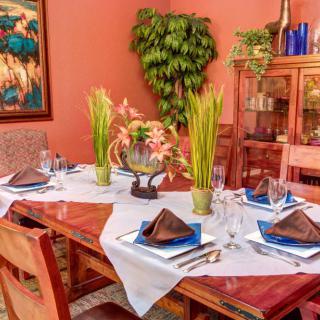 A beautifully set dining table with elegant tableware and decorative plants in a warmly decorated dining room.
