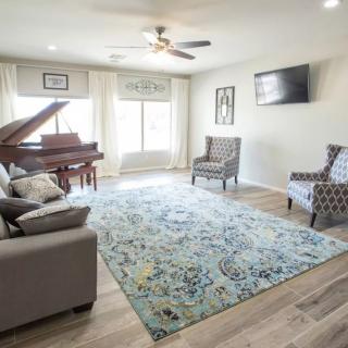 A spacious living room with a grand piano, comfortable seating, and modern decor.