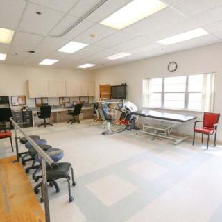 A spacious rehabilitation room equipped with exercise machines, treatment tables, and seating for patients.