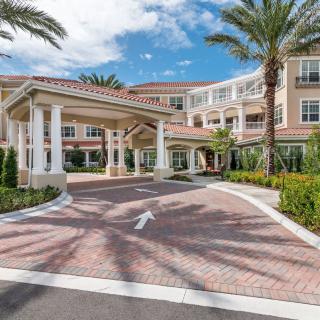 A grand entrance to a residential building lined with palm trees.