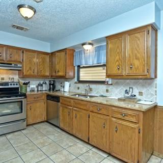 A spacious kitchen with wooden cabinets, stainless steel appliances, and a tiled floor.