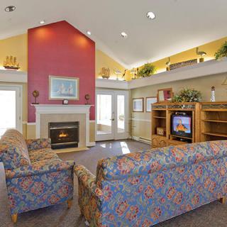 Cozy living room with a fireplace and high ceiling, featuring colorful sofas and a television.