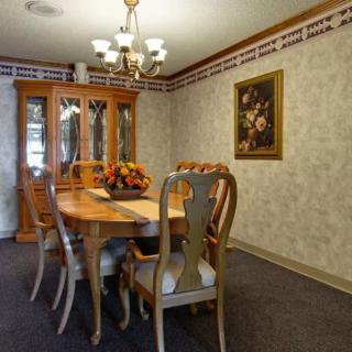 A cozy dining room with an elegant wooden table and chairs, adorned by a chandelier and wall art.