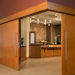 A modern cafe entrance with wooden sliding doors and stylish interior lighting.