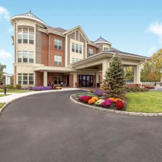 A modern multi-story building with a landscaped entrance and driveway.