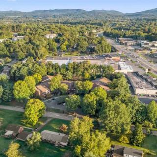Aerial view of a suburban area surrounded by lush trees and distant mountains.