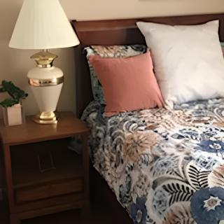 A cozy bedroom setup with a bedside lamp and floral bedding.