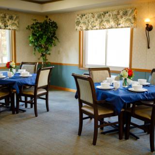 A cozy dining room with tables set for a meal, featuring blue tablecloths and elegant decor.