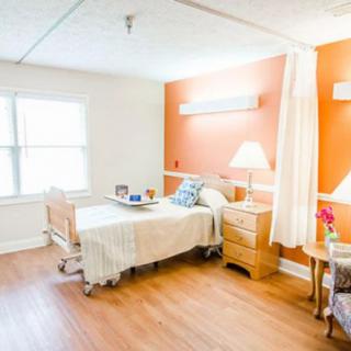 A clean and well-lit hospital room with a bed, nightstand, and window.