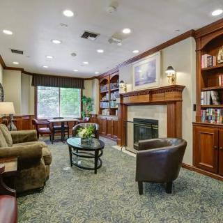 A cozy living room with a fireplace, armchairs, and built-in bookshelves.
