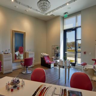 A well-appointed salon interior featuring red chairs, mirrors, and various beauty products.
