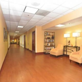 A spacious hallway with wooden flooring and a cozy seating area illuminated by stylish lamps.