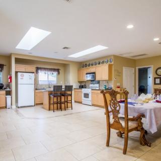 A spacious modern kitchen with wooden cabinets and a dining area, featuring skylights and tiled flooring.