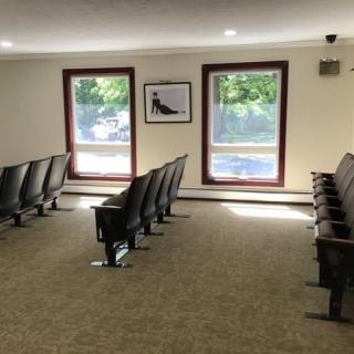 A quiet waiting room with rows of chairs and large windows providing natural light.
