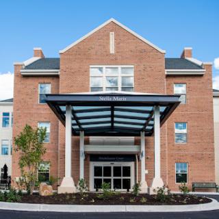 A modern brick building with a glass canopy entrance.