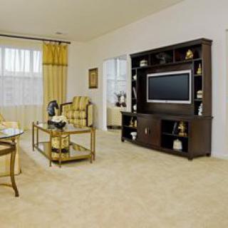 A cozy living room with a television and entertainment center, featuring comfortable seating and elegant decor.