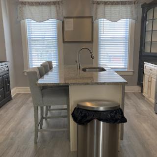 A contemporary kitchen featuring a central island, bar stools, and ample natural light from large windows.