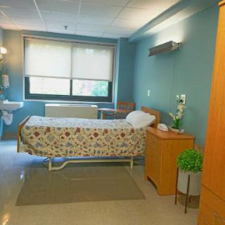 A well-organized hospital patient room featuring a bed, functional furniture, and a calming blue color scheme.
