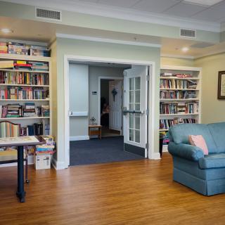 A cozy library room with bookshelves, a couch, and wooden flooring.
