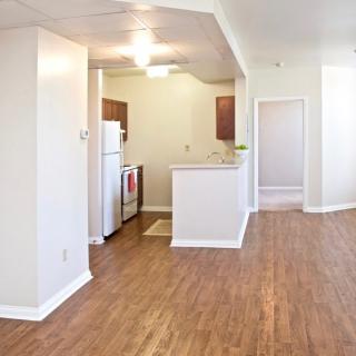 A modern apartment interior with an open kitchen layout and wood flooring.