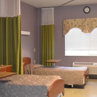A hospital room with two beds, green privacy curtains, and a window.