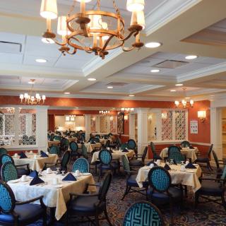 An elegant dining room with neatly arranged tables and chairs, illuminated by stylish chandeliers.
