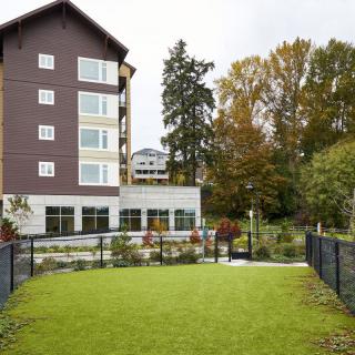 An apartment building with a well-maintained lawn and surrounding trees.