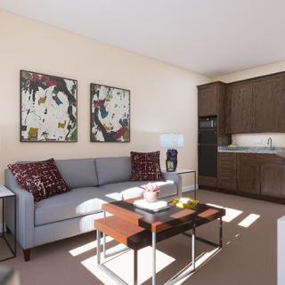 A modern living room with a sofa, coffee table, and kitchenette, adorned with abstract artwork.