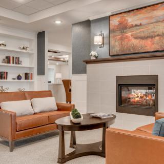 A cozy and beautifully decorated living room with modern furniture, a fireplace, and artwork above the mantel.
