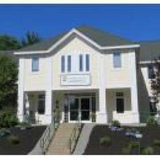 A front view of a two-story building with an entrance and stairs leading up to it.