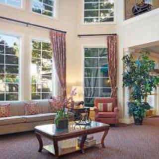 A spacious living room with large windows, elegant furniture, and decorative elements.