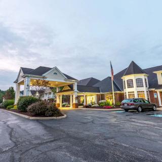 An exterior view of a hotel with a spacious parking lot and illuminated entrance.