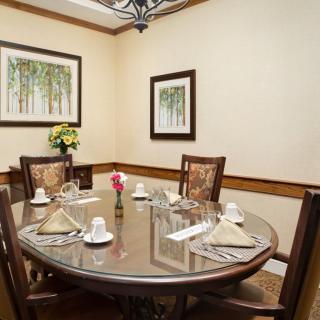 A well-appointed dining room with a round table set for four, adorned with artwork and flowers.